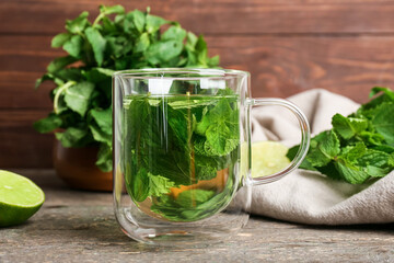 Glass cup of tasty mint tea on wooden background