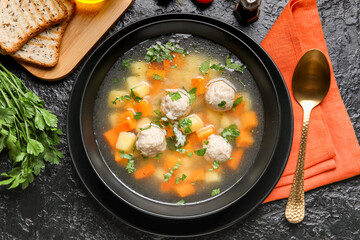Bowl with tasty meatball soup on dark background