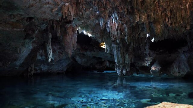 Tilt up shot of a beautiful underground Mexican Cenote with Stalactites growing from the roof and crystal clear blue fresh water in a eco-park Kantun Chi on Playa del Carmen in Riviera Maya, Mexico