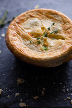 One Individual Serving Sized Chicken Pot Pies With A Perfectly Golden Flaky Crust With A Fresh Thyme Garnish On A Grey Slate Background.