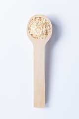 A single wooden measuring spoon of dried minced onion isolated on a plain white background with a light shadow. 