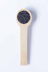 A single wooden measuring spoon of poppy seeds isolated on a plain white background with a light...