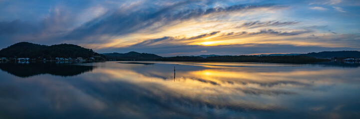 Sunrise and cloud reflections panorama waterscape at Woy Woy on the Central Coast of NSW, Australia.