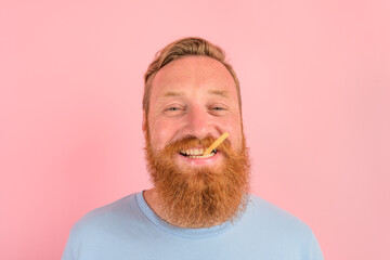 Happy man with beard and tattoos eats fried potatoes