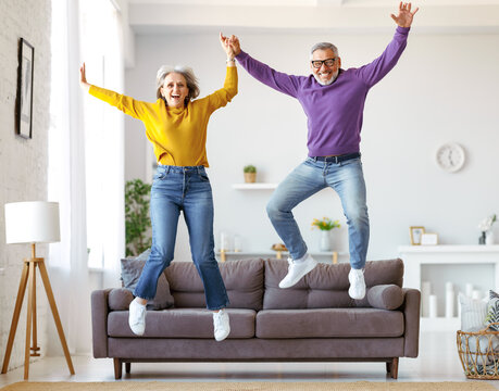 Full Length Of Happy Active Energetic Senior Caucasian Family Couple Jumping And Having Fun Together