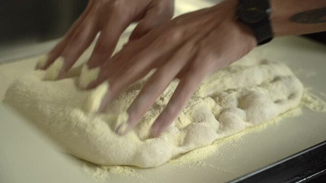 Pizzaiolo hand-stretching roman high hydration pizza dough. Extreme closeup