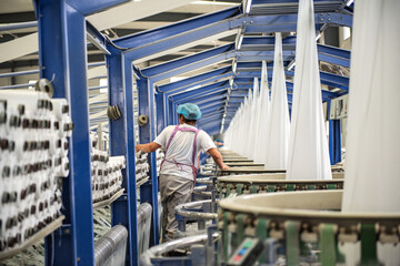 Tangshan city, Hebei Province, China -- June 13, 2021: Machinery is running and workers are working in a bag weaving workshop of a packaging plant.