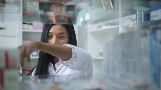 Asian pharmacists working and checking drug in pharmacy store at hospital. Asian doctor checking medicine cabinet and wearing white medical coat. Shelves pharmacy background in drugstore.