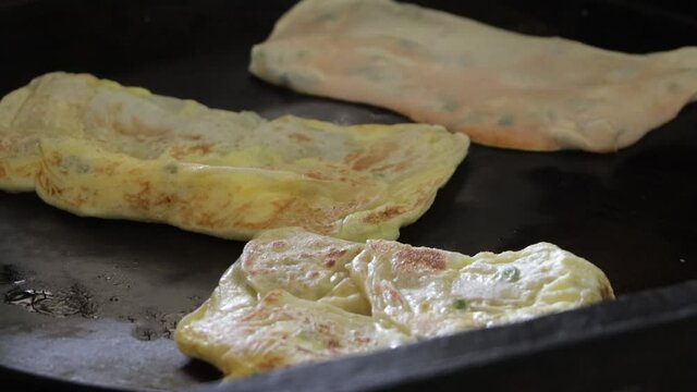 The Seller Of Roti Canai Or Roti Maryam Is Cooking By Frying On A Frying Pan