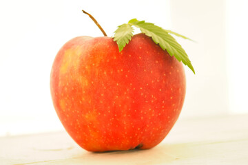 hemp leaf lies on a ripe red apple