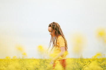 Pretty long haired girl playing in vibrant canola field in full bloom