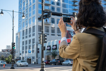 Brunette woman on her back taking a smart phone picture of a city