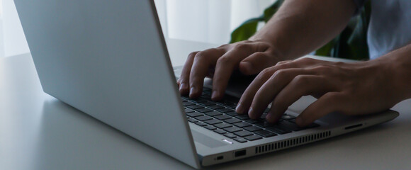 Close up young man working on laptop. Work from home banner.