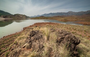 View of Zameer gul dam, district, Kohat, Pakistan with large rock in the foreground with clear sky.