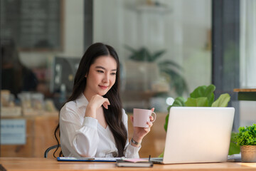 Businesswoman having tea or coffee in home office.