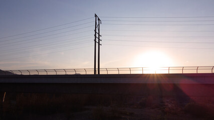 Fototapeta na wymiar Sunset Power Lines and Bridge Silhouette