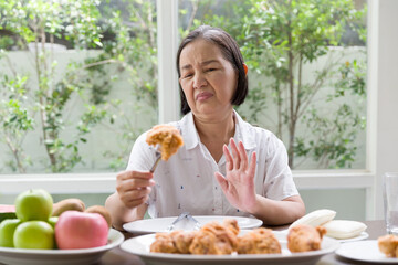 Senior Asian woman don't like fried chicken. Elderly Asian woman don’t eat junk food or fast food. Health care and ageing concept - obrazy, fototapety, plakaty
