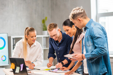 Team of young and confident startupers is working at the table in the office, discussing the strategy and development plan of the company. Business, innovation, brainstorming and teamwork.