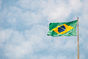 brazil flag outdoors with a beautiful blue sky.