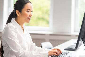 Asian business woman is working at her table in a modern office. The workplace of a successful specialist. Business, confidence and finance.