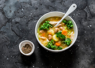 Tuscan style thick chicken, bean soup on a dark background, top view. Delicious autumn comfort food