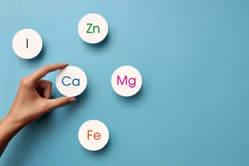 Fotobehang paper circles with inscriptions of vitamins and macronutrients. Choosing calcium from other useful substances © fidaolga