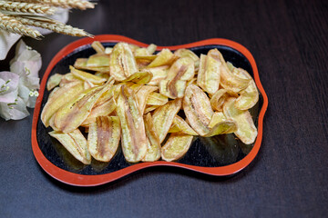 Deep fried sliced banana chips on black plate