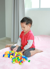 asian little baby boy playing colorful plastic blocks with sitting in which is called W-sitting....
