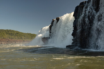 Sailing the river. The majestic Mocona waterfalls seen from the boat. The falling white water, rocks and river flowing across the jungle.