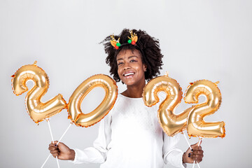 Happy young African American woman holding 2022 gold color balloons for celebrate merry Christmas and happy new year on white background, celebration and decoration for holiday event concept