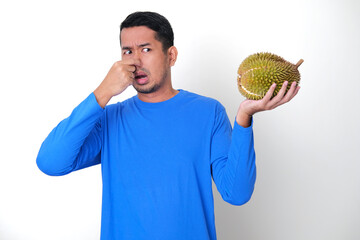 Adult Asian man closed his nose because of bad smell while holding durian fruit