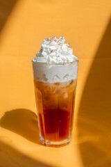 Iced coffee with milk and ice cream on orange background.