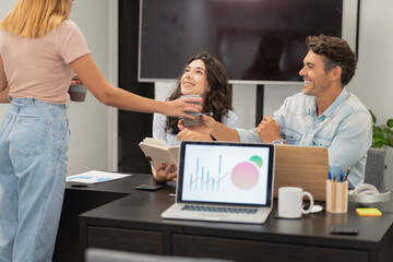 people talking in the background in a coworking while a computer appears in the foreground