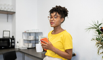 Fototapeta na wymiar afro woman drinks coffee in an office kitchen