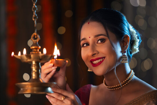 Beautiful Indian wonam lightning a lamp with diya on the occasion of Diwali