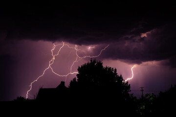 Multiple lightning strikes painting the sky purple on a summer evening during a thunderstorm
