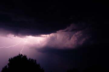 Multiple lightning strikes painting the sky purple on a summer evening during a thunderstorm