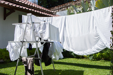 white bedding, clothesline drying, hanging outside. 