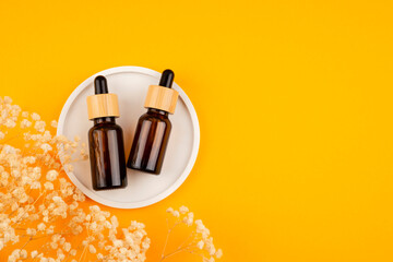 Amber glass dropper bottles different sizes with bamboo lid on the white podium on an orange background. Presentation backdrop for text or advertising. Beauty concept for face and body care.