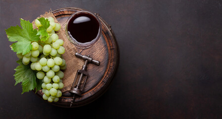 Red wine glass and white grape on old barrel