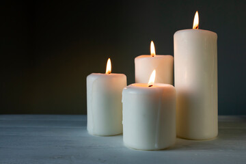 Large burning candles on a dark background. Side view, place for text.