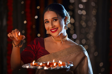 Beautiful Indian lady posing with diyas in front of camera on the occasion of Diwali