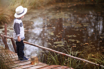 A child is fishing in the autumn morning. Autumn sunset on the pond. A fisherman with a fishing rod on the walkway.