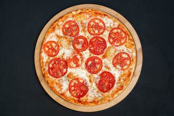 Pizza Margherita with Tomatoes on black stone background, top view.