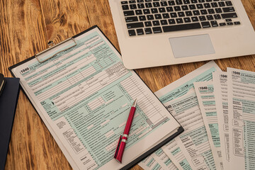 Obraz premium on a wooden table lie a laptop, American tax forms with a tablet and a pen