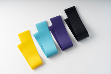 A set of colorful elastic fitness band. Expanders for women and weight loss on white background Flat layer of various fitness bands, space for text Elastic elastic bands for fitness, selective focus