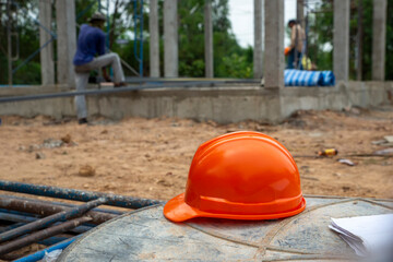 Safety helmet (hard hat), blueprint, and drawings paper for engineer, safety officer or architect, place on wooden floor. Orange safety hat (helmet) in construction site.