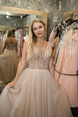 charming young lady has chosen the perfect evening dress in a clothing store and poses in it