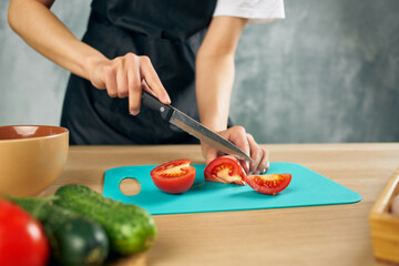 Cook woman on the kitchen cutting vegetables isolated background