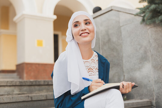 Female middle eastern college student sits on stairs in university campus. Education and knowledge concept.